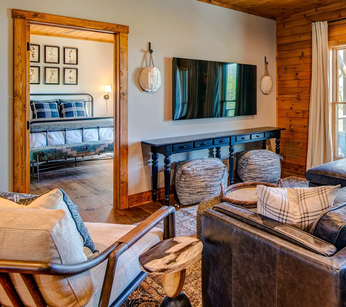 This interior scene presents a comfortable seating area with decorative wall art, a television, and a doorway leading to a bedroom. The area is designed for relaxation, entertainment, and family time, with a cozy, welcoming mood.