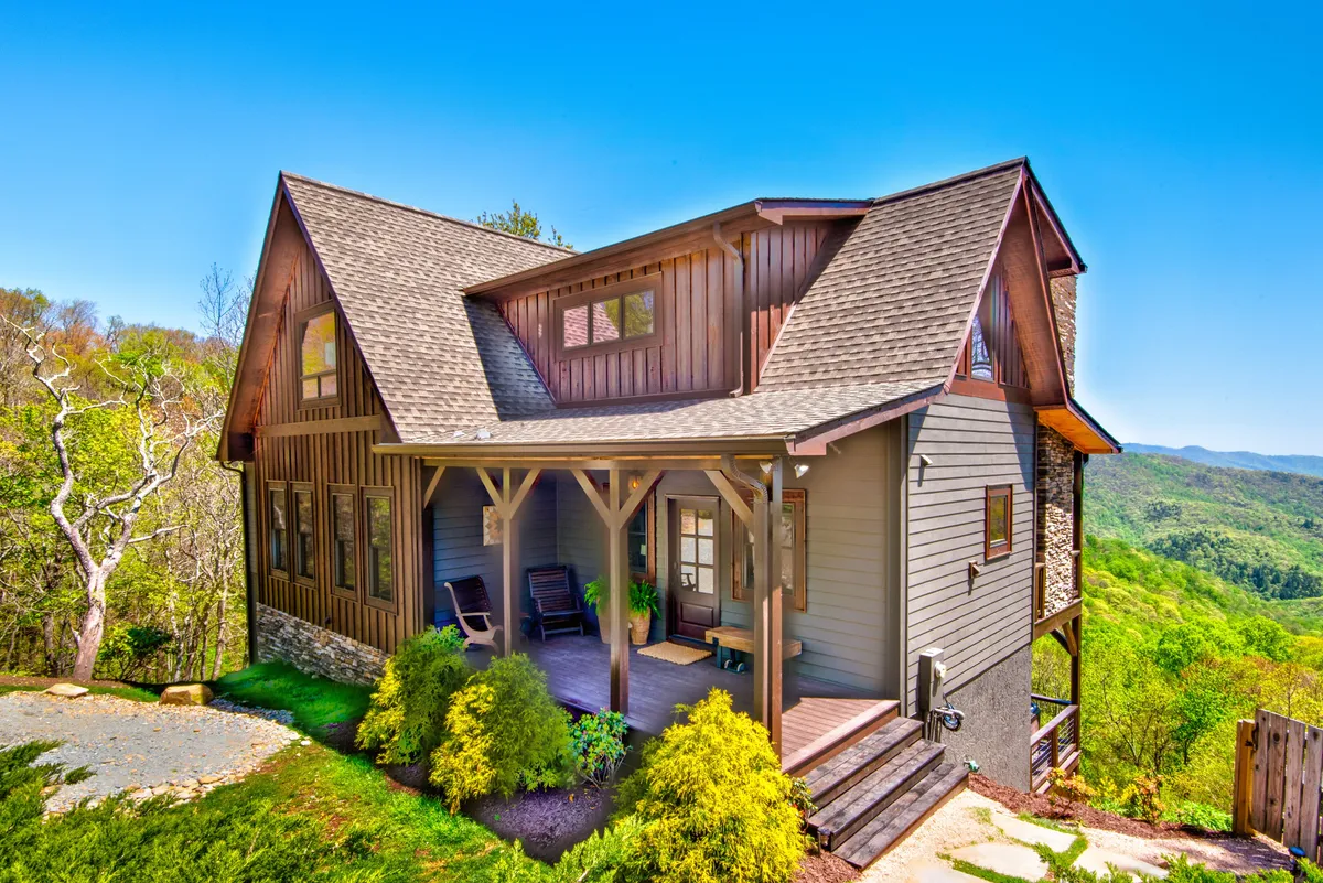 This image showcases the front porch of Owl’s Nest, featuring inviting rocking chairs and a stone and wood exterior, with panoramic mountain views visible in the background. The porch sits adjacent to the home’s entry, offering a sense of welcome and relaxation.