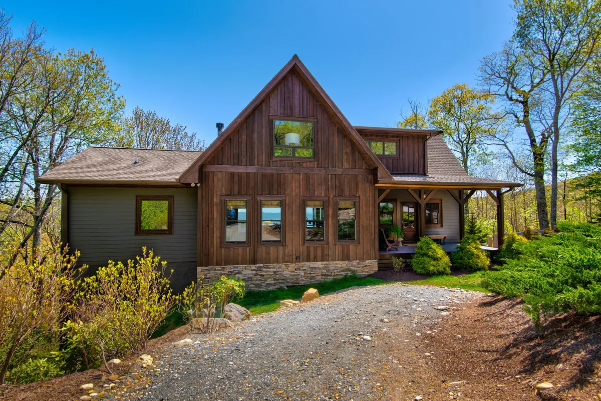 Here, the image highlights the wooden and stone exterior of the home, with large windows and a view of the front porch. The architectural details reinforce the rustic yet welcoming atmosphere, inviting both guests and their pets to feel at ease.